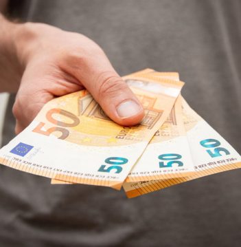 A closeup shot of a young man holding 150 euros in his hand